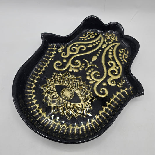 Hamsa hand trinket dish with black glaze, intricate gold-toned evil eye and mandala detailing